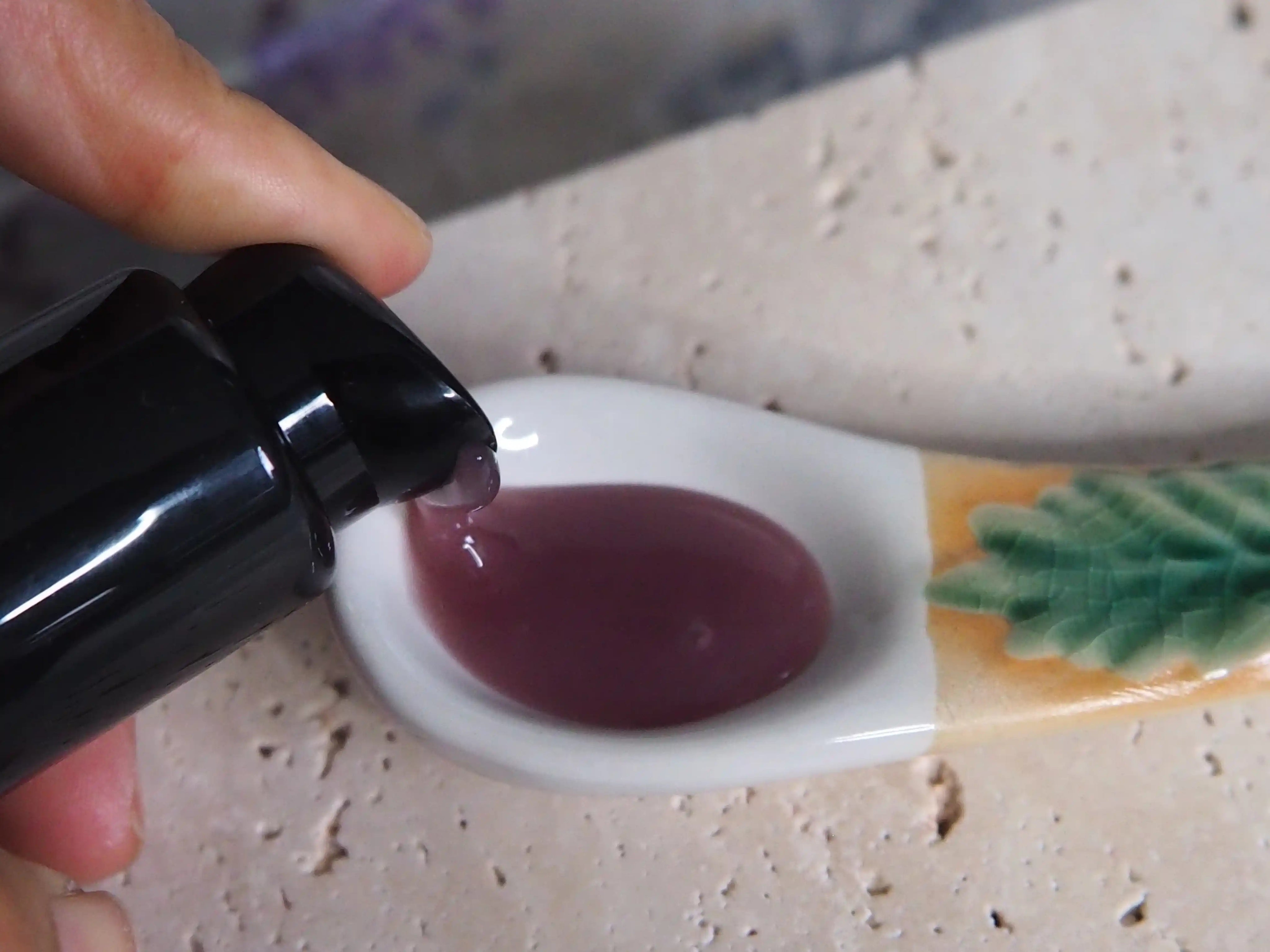 Purple gel mask being pumped out of the beautiful black bottle to show the texture.