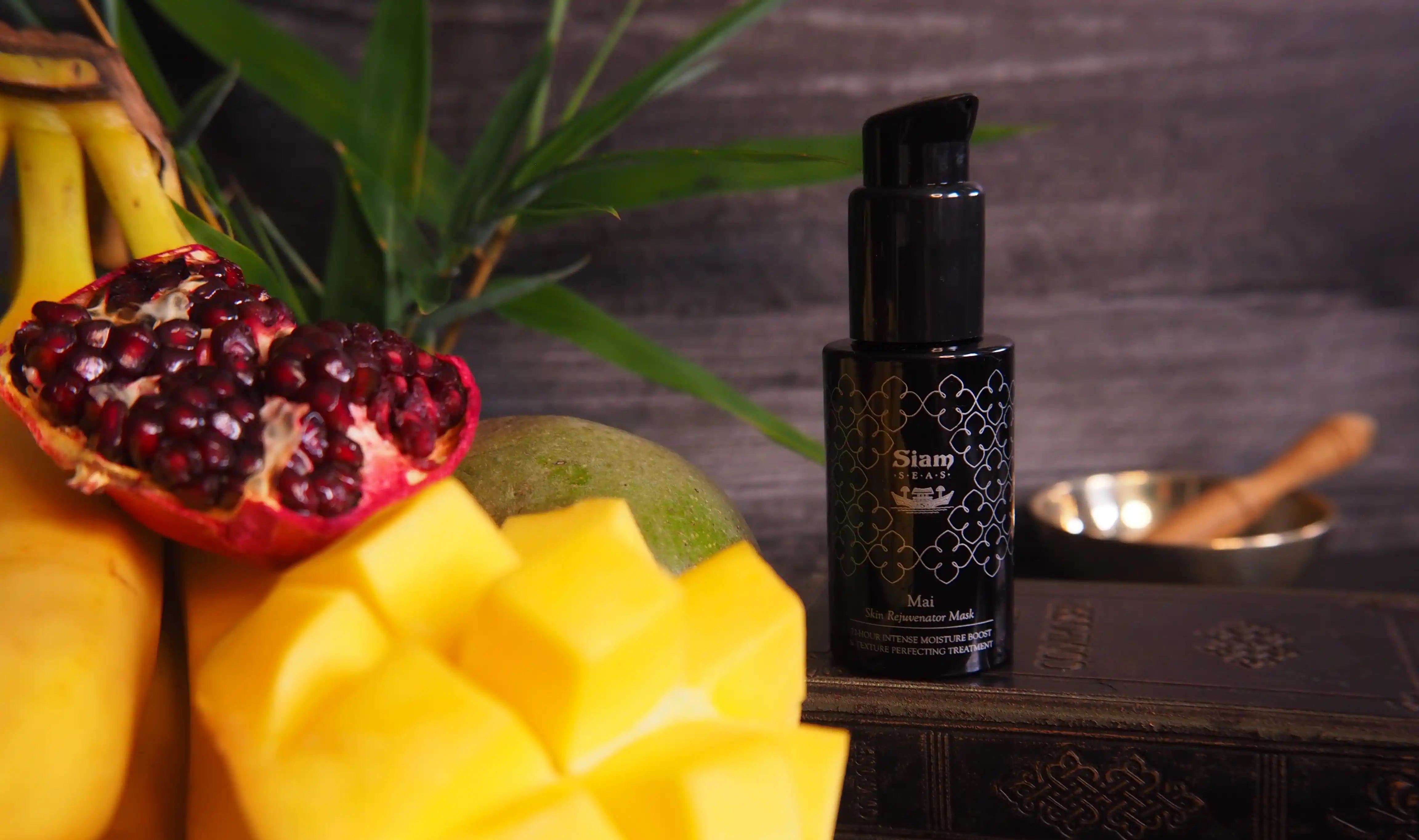 Black bottle with geometric design on a wooden surface with fruits in the background
