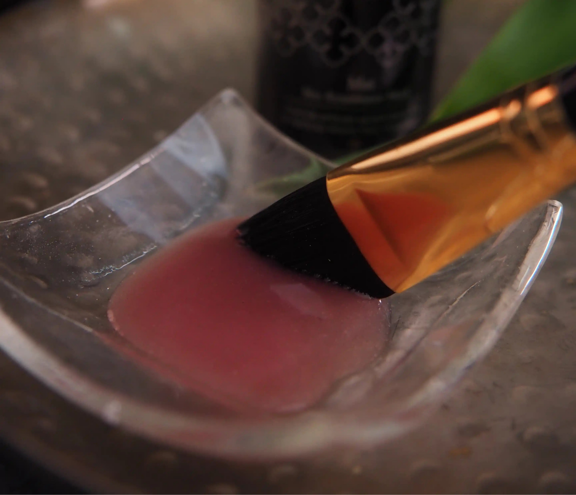 Pink mask on a metallic surface with a black bottle in the background