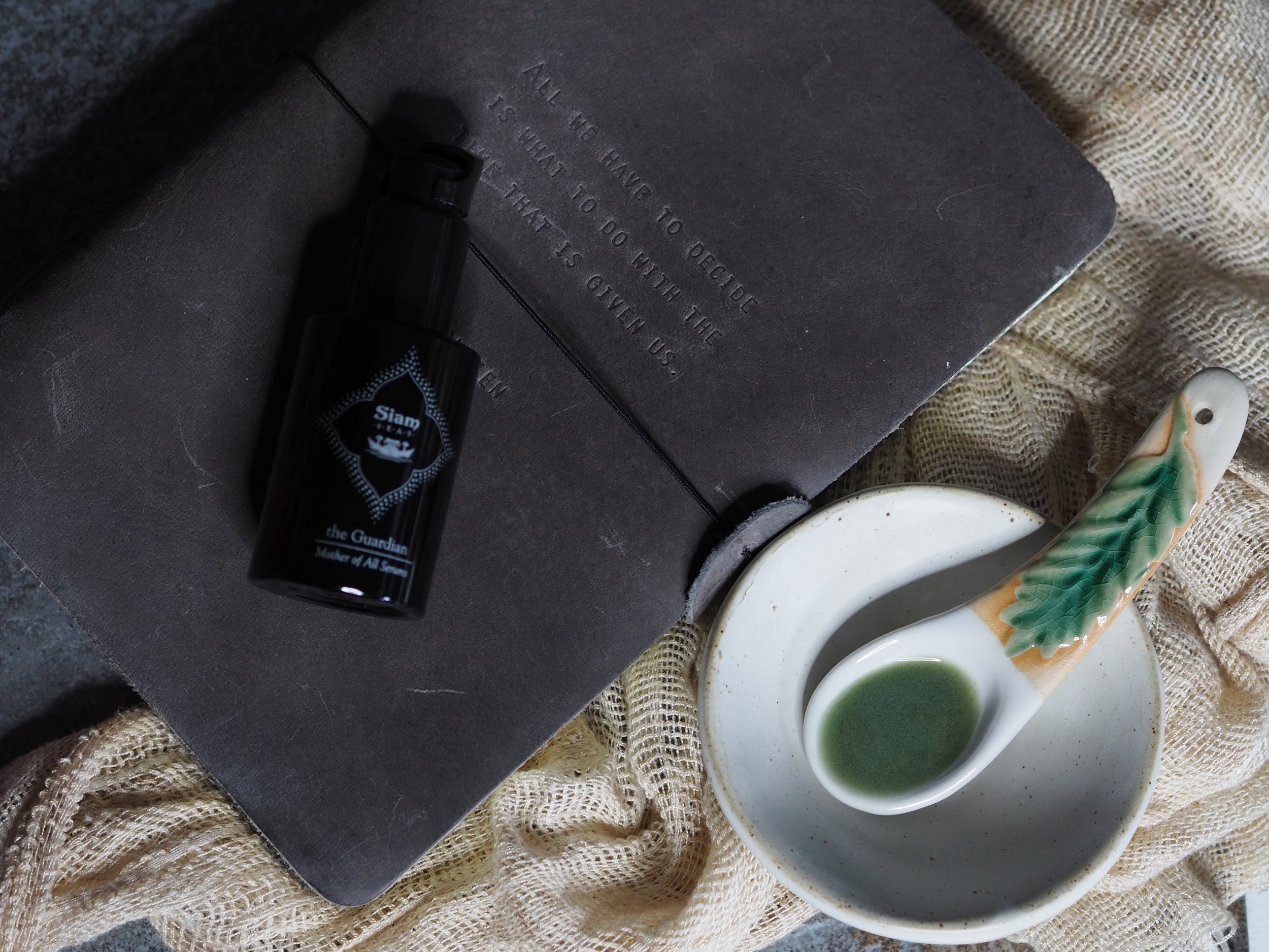 The guardian DNA repairing in a black glass bottle on a journal with its texture on the spoon.